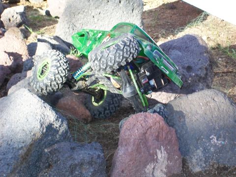 1985 Ford Bronco - A green remote control rock crawler navigates a rocky terrain.