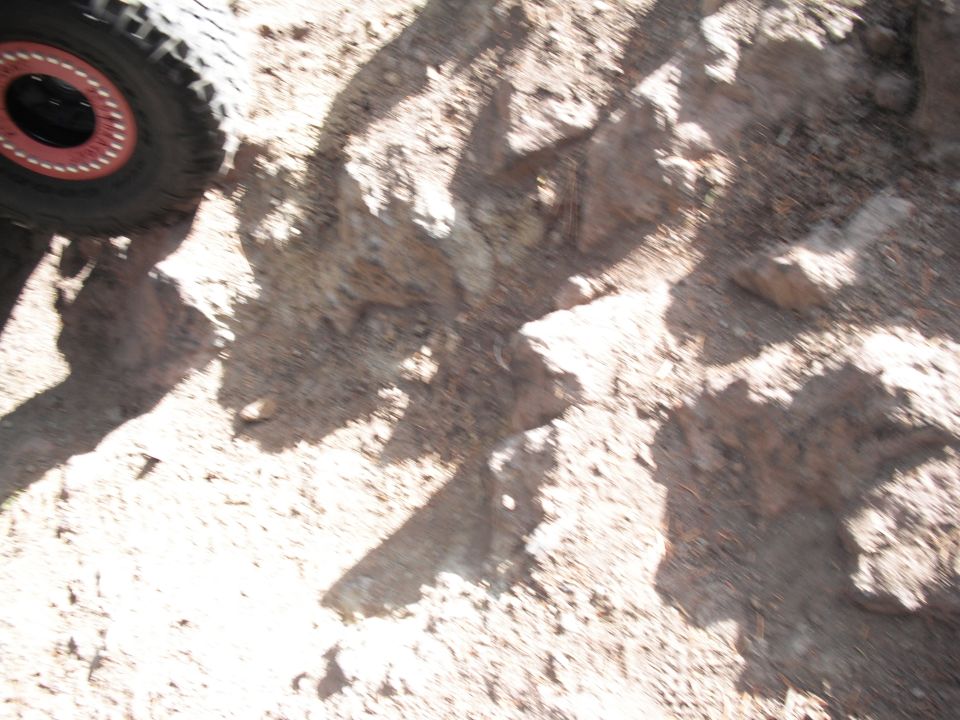 Tire with red-accented rim on rocky ground