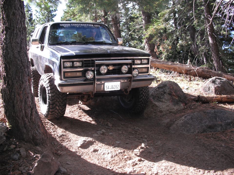 Black SUV with off-road tires on a rocky trail. "UNDER CONSTRUCTION 4X4" sticker on windshield