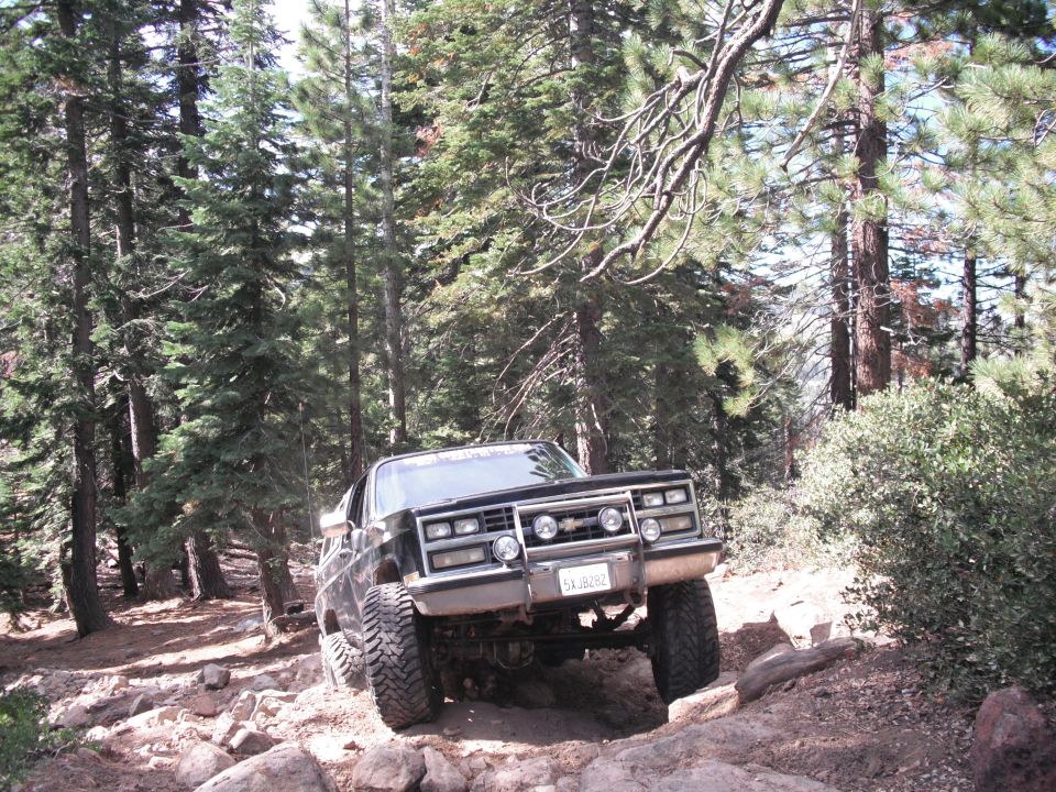 Black off-road SUV with aftermarket grille guard and large tires navigating a rocky trail
