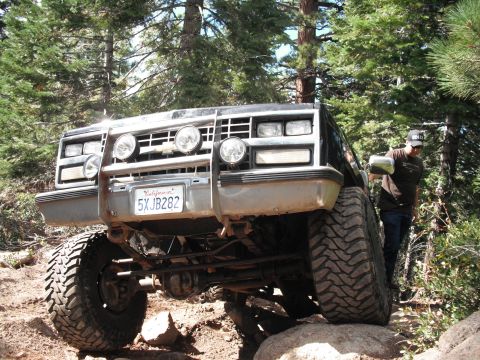 1991 Ford Bronco - A black truck navigates a challenging off-road trail, its front end angled towards the viewer.