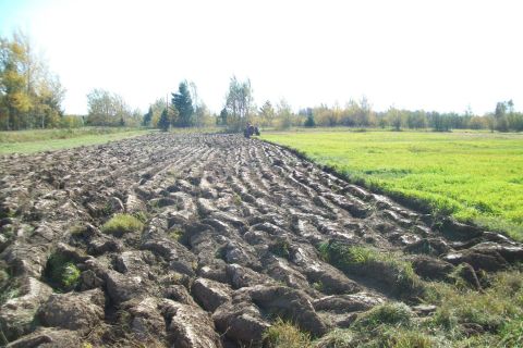 2000 Chevrolet Tahoe - A tractor is plowing a field, leaving behind freshly turned earth in rows.