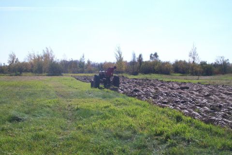 2000 Chevrolet Tahoe - A tractor is seen plowing a field under a clear blue sky, with trees and foliage in the background.