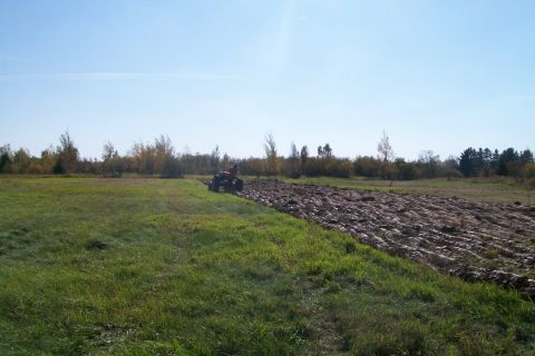 2000 Chevrolet Tahoe - Tractor plowing a field with tilled soil visible.