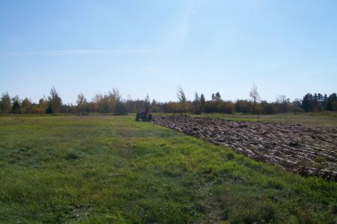 2000 Chevrolet Tahoe - A tractor is seen plowing a field on a clear day, with trees in the background.
