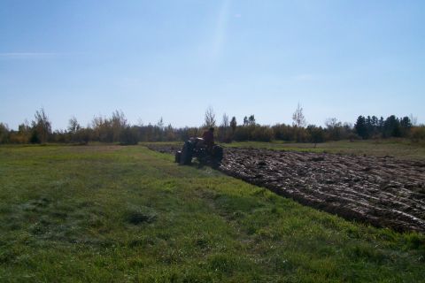 2000 Chevrolet Tahoe - Tractor plowing a field on a sunny day with trees in the background.