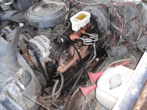 1991 Ford Bronco - The engine bay of a vehicle shows various components including the alternator and brake fluid reservoir.