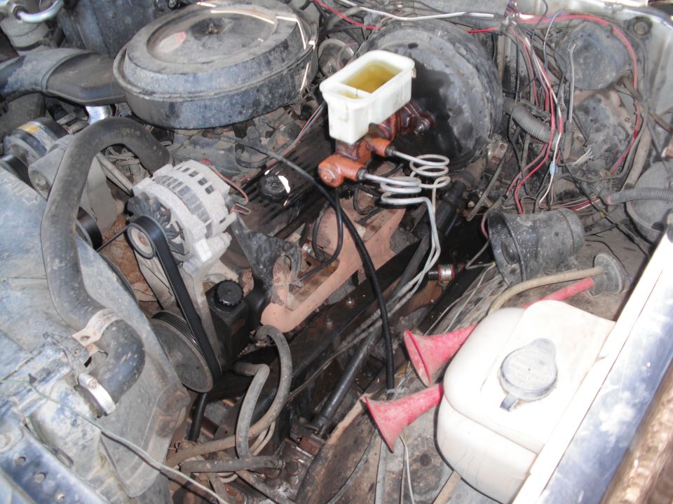 Engine bay with alternator, brake fluid reservoir, and hoses visible