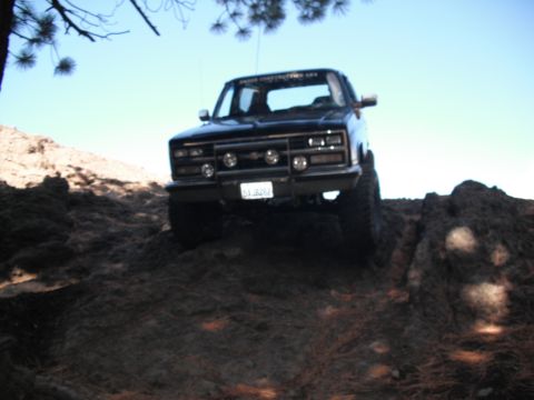 1991 Ford Bronco - This black pickup truck appears to be from the early 1990s, possibly a Chevrolet or GMC, navigating rough terrain.