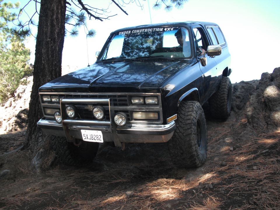 black SUV with off-road tires on rocky terrain, "UNDER CONSTRUCTION 4X4" sticker on windshield