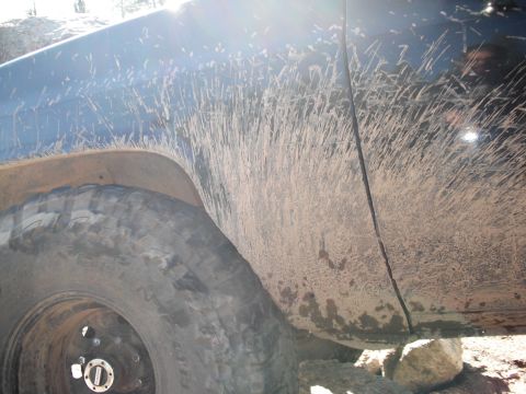 1991 Ford Bronco - Mud covers the side of a vehicle and its tire after off-roading.