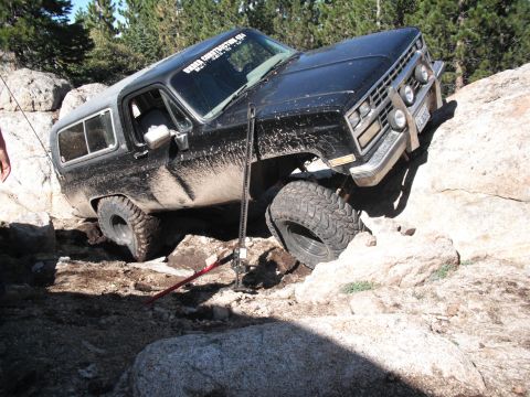 1991 Ford Bronco - This modified SUV is stuck on a rock obstacle, with a high-lift jack visible.