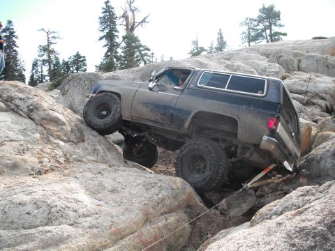 1991 Ford Bronco - This SUV is navigating a difficult rocky terrain, with one wheel lifted high.