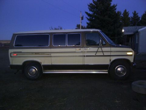 1979 Ford E250 - This van is parked outside a house at dusk, showing its side profile with tinted windows and chrome trim.