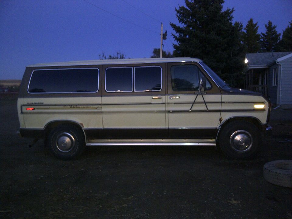 Side view of a 1979 Ford E250 van parked outside at dusk. It has a two-tone paint job with cream and brown