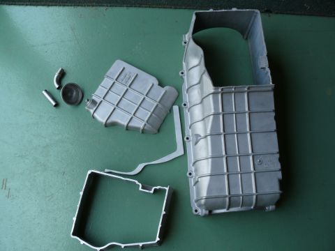1976 Chevrolet Corvette - Disassembled aluminum oil pan assembly laid out on a green surface.