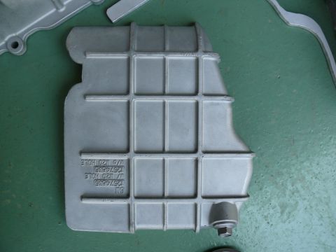 1976 Chevrolet Corvette - A cast aluminum oil pan with a grid pattern and visible part numbers is shown on a green surface.