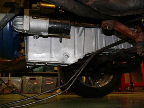 1976 Chevrolet Corvette - Underside view of a vehicle's engine bay, focusing on the starter motor and oil pan assembly.