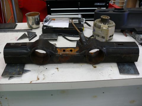 1976 Chevrolet Corvette - A rusty automotive part sits on a workbench, surrounded by tools and metal scraps.