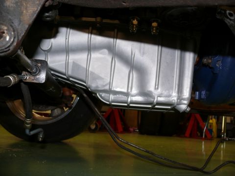 1976 Chevrolet Corvette - A close-up view of the underside of a vehicle, focusing on the oil pan and associated plumbing.