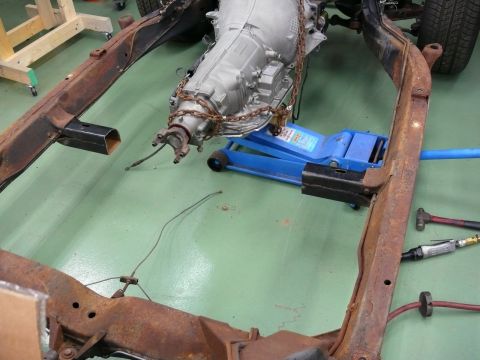 1976 Chevrolet Corvette - Vehicle frame and transmission assembly on a green floor, with tools nearby.