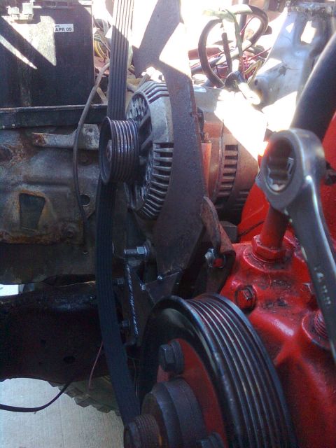1984 Ford Bronco - Close-up view of engine components, including pulleys and an alternator, with a wrench nearby.