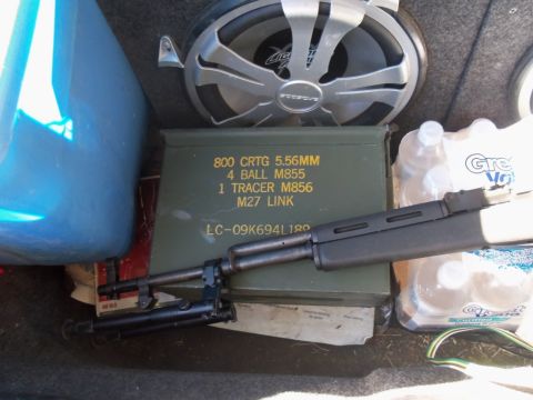 2000 Mercury Grand Marquis - Contents of a car trunk include an ammo can, rifle, water bottles, and a blue container.