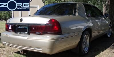 2000 Mercury Grand Marquis - The rear of a gold 2000 Mercury Grand Marquis is visible, parked outdoors with a tree and building in the background.
