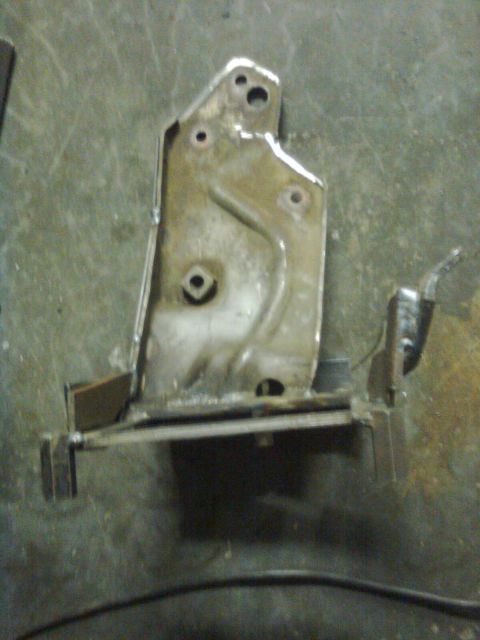 1984 Ford Bronco - A close-up view of a metal bracket, possibly a vehicle part, on a textured surface.