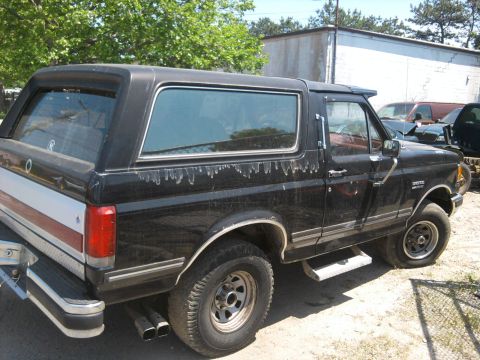 1989 Ford Bronco - This black Ford Bronco shows signs of wear and tear, with a distinctive body style.