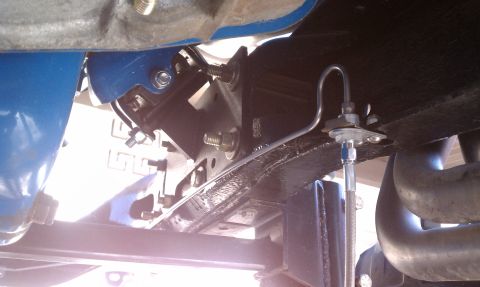 1979 Ford Bronco - Underside view of a vehicle's brake system, focusing on a metal brake line and its mounting hardware.