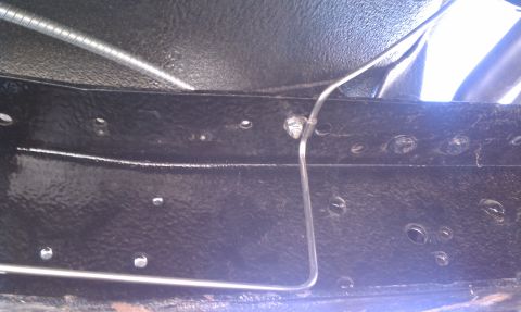 1979 Ford Bronco - Underbody view of a vehicle frame with a brake line attached.