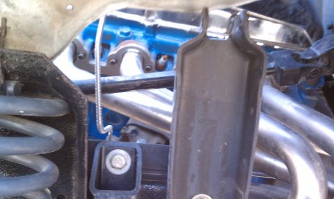1979 Ford Bronco - The engine bay features shiny exhaust headers and a blue painted engine block, with a suspension spring visible.