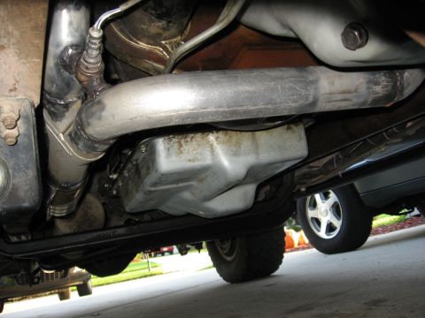 1994 Ford Bronco - The underside of a vehicle reveals exhaust components and an oil pan, with another vehicle visible in the background.