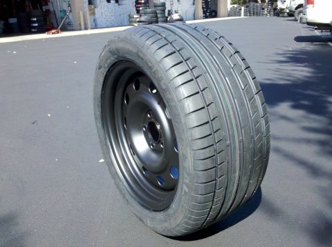 2004 Ford Crown Victoria - A close-up of a new tire and steel wheel, likely a spare or replacement part, displayed outdoors.