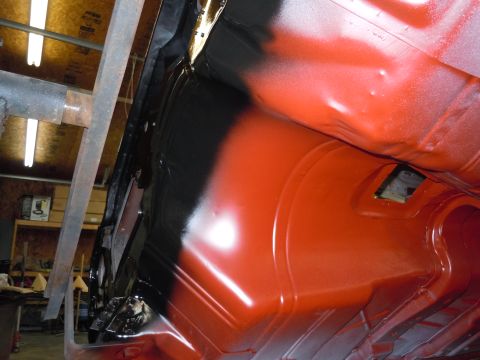 1973 Pontiac Trans Am - The undercarriage of a vehicle is being painted with red and black spray paint.