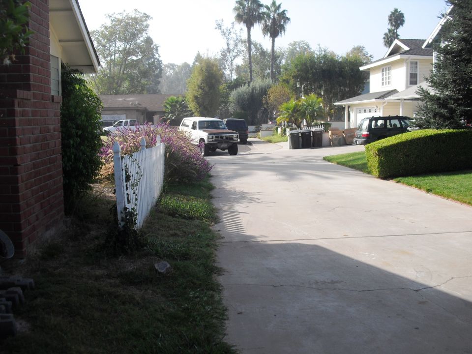 White 1980s Ford Bronco with brown top parked on driveway, front 3/4 view
