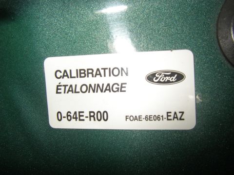1990 Ford Bronco - Close-up of a white Ford calibration/étalonnage sticker reading "0-64E-R00" and "F0AE-6E061-EAZ" with the Ford oval logo, affixed to a dark…