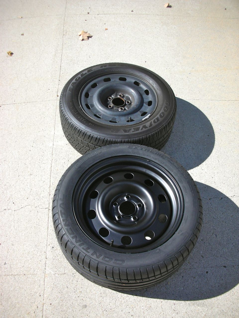 Two spare tires, one Goodyear Eagle, one Continental, on concrete