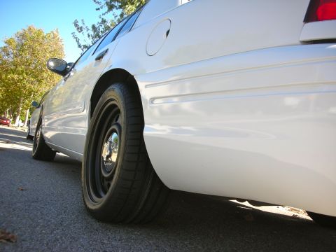 2004 Ford Crown Victoria - A white 2004 Ford Crown Victoria is viewed from the side, highlighting its steel wheels and clean body lines.