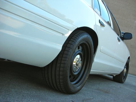 2004 Ford Crown Victoria - Close-up of the rear wheel and fender of a white 2004 Ford Crown Victoria.