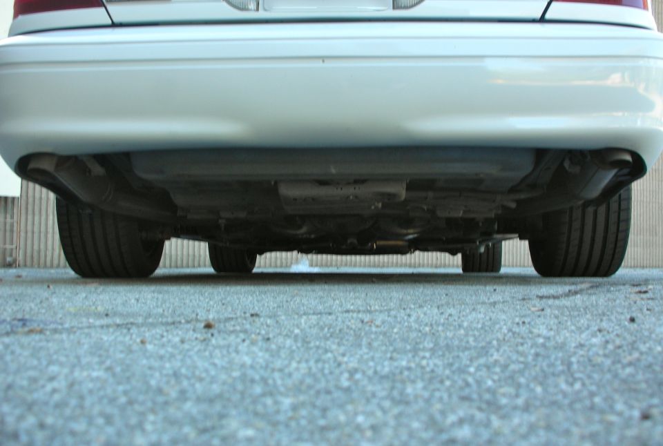 Rear underside of a white 2004 Ford Crown Victoria showing exhaust and tires