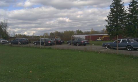 2007 Ford Crown Victoria - Several sedans are parked in a lot under a cloudy sky.