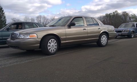 2007 Ford Crown Victoria - Gold 2007 Ford Crown Victoria seen from the side with another vehicle in the background.
