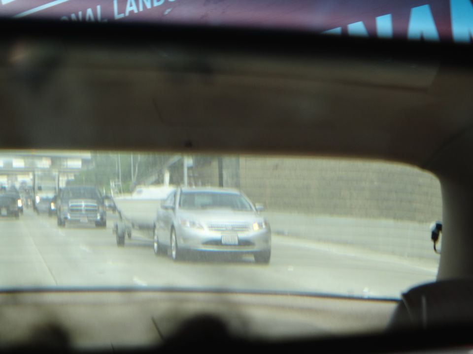 Silver sedan towing a boat trailer on a highway, front view