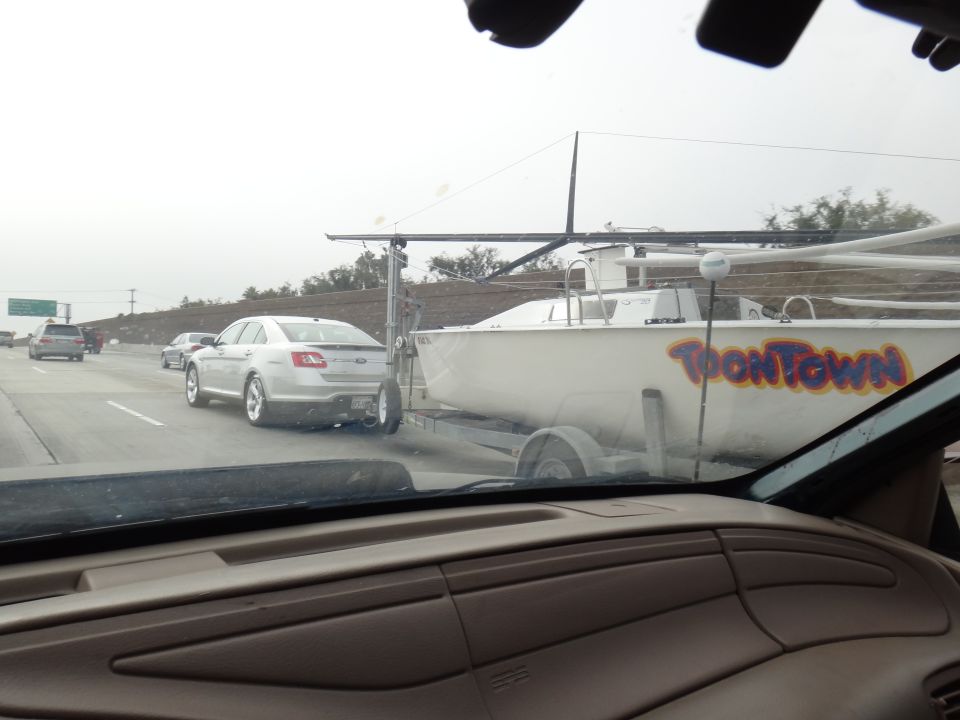 Silver sedan towing a boat trailer with 'ToonTown' text, rear view