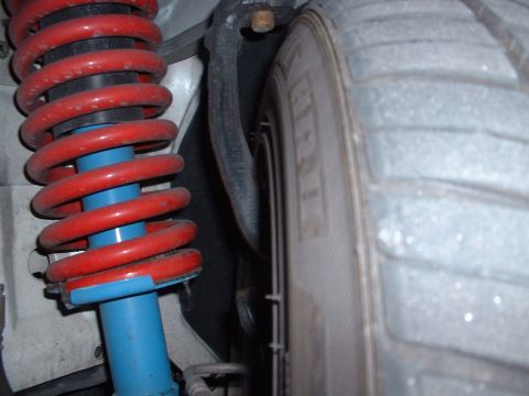 1997 Mercury Cougar - Close-up of a red coilover suspension system and a tire, likely from a vehicle's undercarriage.