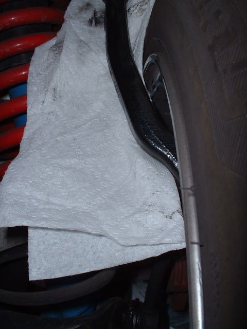 1997 Mercury Cougar - Close-up view of vehicle suspension components, including a red coil spring and black control arm, with a tire visible.