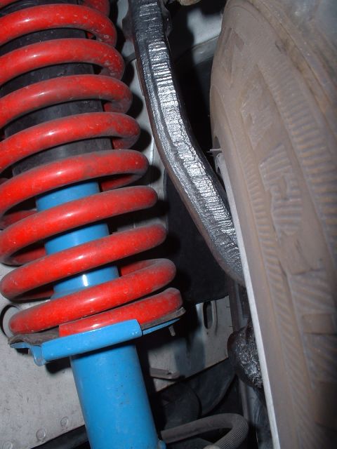 1997 Mercury Cougar - Close-up of a vehicle's suspension system, showing a red coil spring and blue shock absorber.