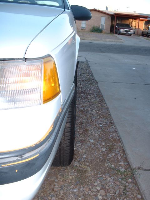 1997 Mercury Cougar - The front corner of a white sedan is visible, parked near a residential house with another vehicle in the driveway.
